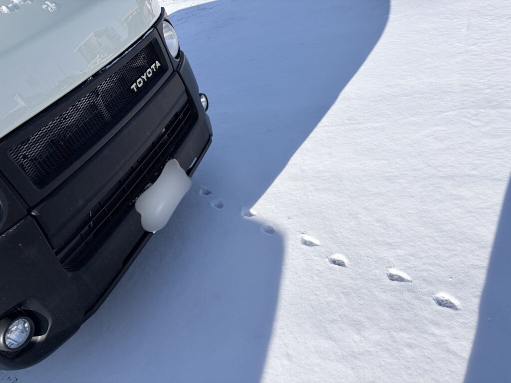 雪上に停車したライトイエローのハイエース200系ディーゼル4WDをフロント側から撮影した冬の様子